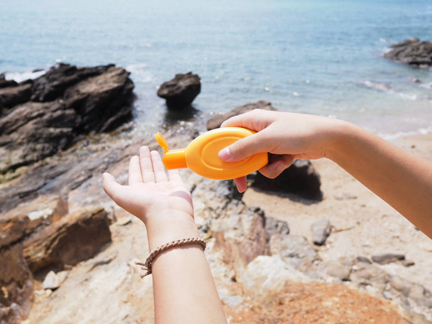 hand holding sunblock cream bottle on the beach - Photo, Image