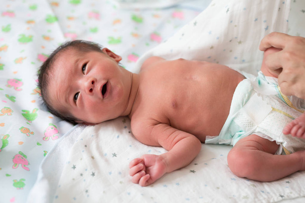 Aziatische baby jongen is het dragen van luiers na het Baden op bed, tien dagen oud - Foto, afbeelding