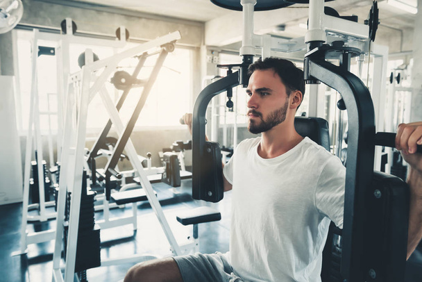 Όμορφος άντρας είναι άσκηση με θωρακικά μηχάνημα στο γυμναστήριο - Φωτογραφία, εικόνα