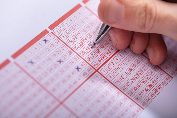 Close-up Of A Person Marking Number On Lottery Ticket With Pen - Foto, afbeelding