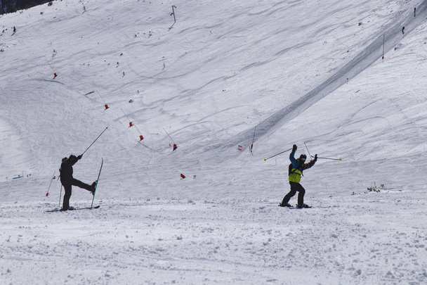 Twee mannelijke skiërs Welkom andere skiërs op de afdaling. Skiërs geluk en enthousiasme tonen na het springen. Vreugde van het verkeer. Jongens zijn in sportkleding. Felicitatie - Foto, afbeelding
