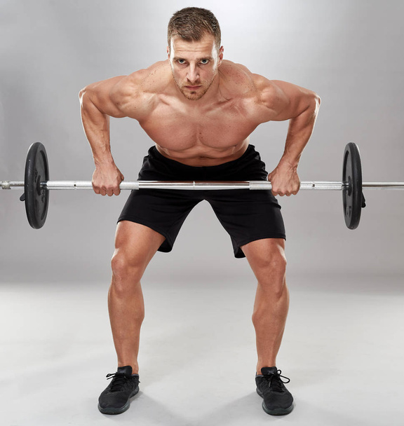Man doing back workout, barbell row in studio over gray background - Foto, Imagen