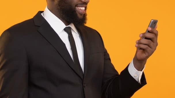 Glad black man in suit holding smartphone showing yes gesture, business e-mail - Metraje, vídeo
