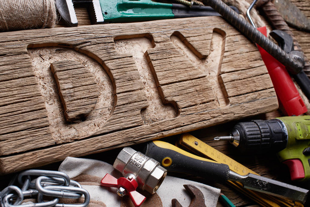 DIY letters on a wooden board on the background of working tools. Do It Yourself concept. - Фото, зображення