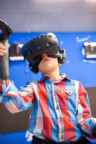 modernin teknologian, pelaamisen ja ihmisten konsepti - poika virtuaalitodellisuuskuulokkeissa tai 3D-lasit pelaamassa videopeliä pelikeskuksessa
 - Valokuva, kuva