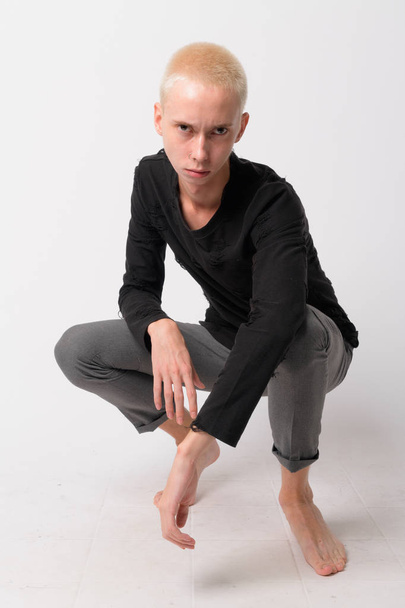 Full body shot of young handsome androgynous man crouching - 写真・画像