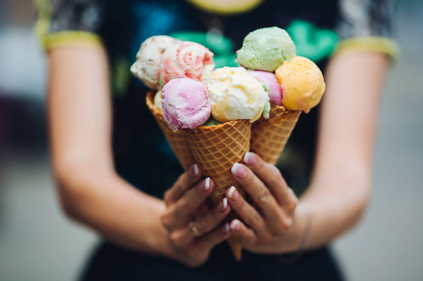 Crop of womans hand holding delicious colorful ice cream. - Фото, изображение
