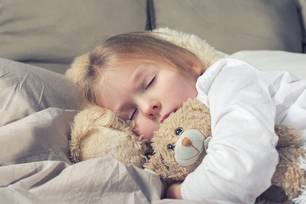 a kislány-játék medve az ágyban alszik - Fotó, kép