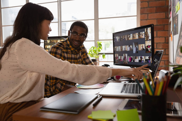 Вид спереду на різноманітних бізнесменів, які обговорюють ноутбук в офісі. Вони дивляться один на одного
 - Фото, зображення