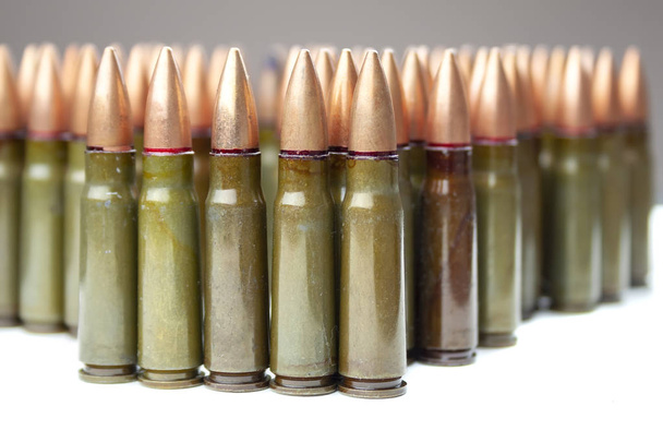 Veel groen en een bruin 7.62 mm cartridge voor Kalashnikov assault rifle - Foto, afbeelding