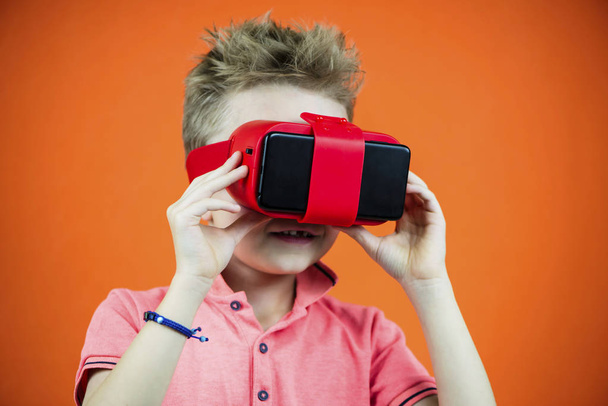 funny boy in virtual reality glasses playing smartphone on orange background - Zdjęcie, obraz