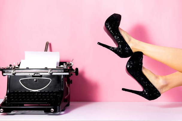 Moda blogger minimalne różowy koncepcja kreatywnych z maszyny do pisania i kobiety szczupłe nogi nosić wysokie obcasy. Retro do pisania. Fetysz Buty. - Zdjęcie, obraz