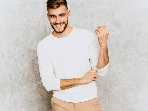 Portrait of handsome smiling hipster lumbersexual businessman model wearing casual summer white clothes. Fashion stylish man posing against gray wall - Fotografie, Obrázek