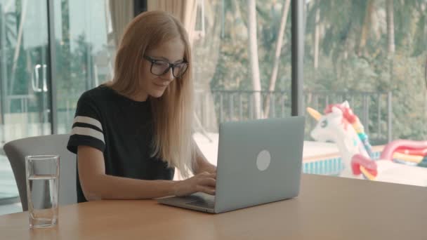 Blonde woman sits at table at home on laptop during the day. freelance concept - Filmmaterial, Video