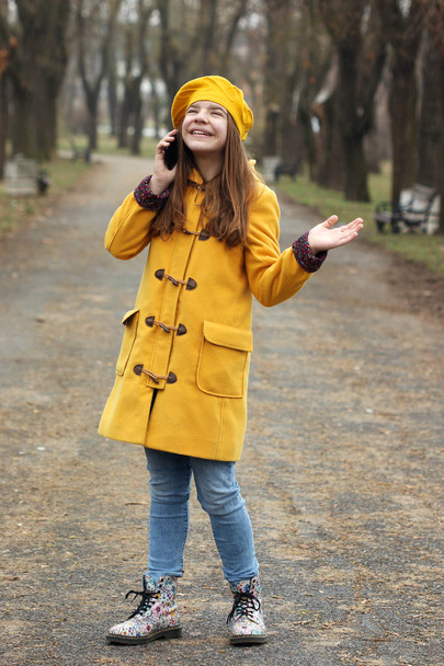 Gelukkig tienermeisje praten op haar smartphone terwijl het regent - Foto, afbeelding