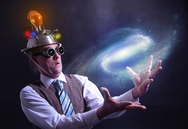 radeloos op zoek samenzwering gelovige in pak met aluminiumfolie hoofd houden de galaxy of universum in zijn handen - Foto, afbeelding