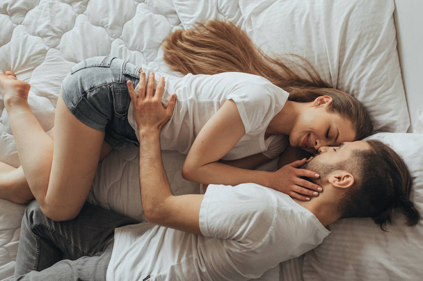 Beautiful loving couple kissing in bed - Фото, зображення