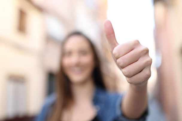 Unfocussed woman gesturing thumb up in the street - Фото, изображение