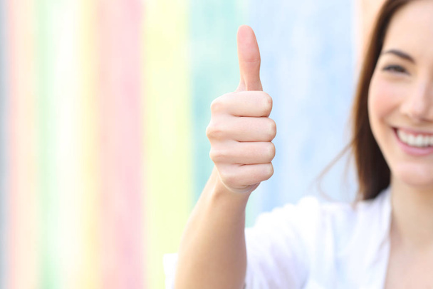 Happy woman gesturing thumbs up in a colorful street - Foto, imagen