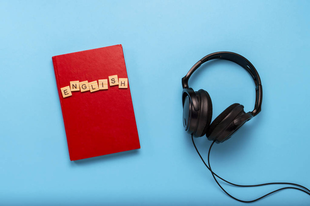 Metin İngilizce ile kırmızı kapaklı kitap ve siyah kulaklık  - Fotoğraf, Görsel