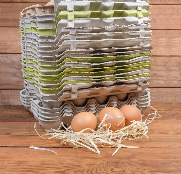 Κοτόπουλο αυγά εναντίον της στοίβας άδειο πολτό τα χαρτοκιβώτια αυγών - Φωτογραφία, εικόνα