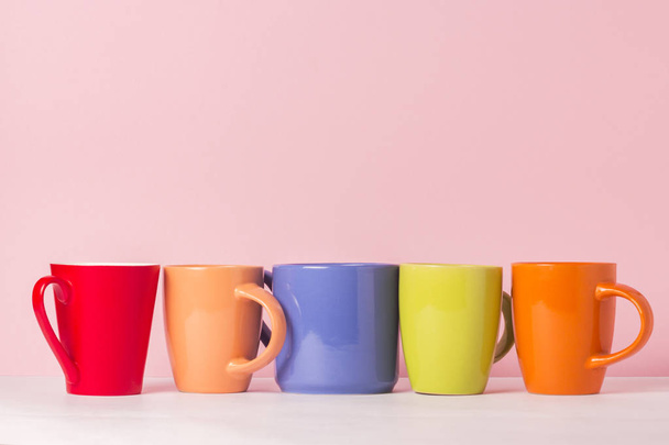 Una gran cantidad de tazas multicolores de café o té sobre un fondo rosa. El concepto de una empresa amigable, una familia numerosa, reunirse con amigos para una taza de té o café
 - Foto, Imagen