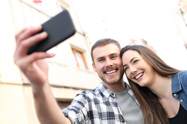 Happy couple taking selfies with smartphone in the street - Foto, imagen