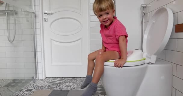 Ładny maluch chłopiec siedzi na toalecie w łazience - Materiał filmowy, wideo