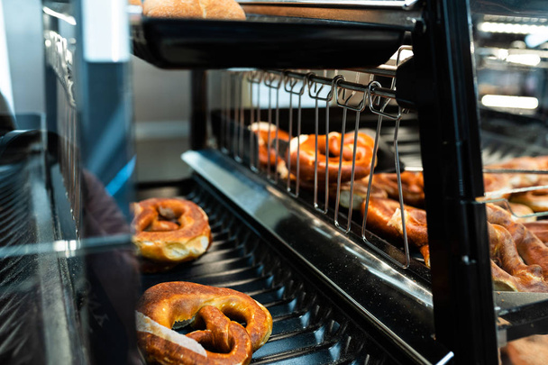Germany national bakery - brezel. Fresh pretzel on bread shelf in store. Take a fresh bavarian Brezel with a spatula. Breakfast food concept - Photo, image