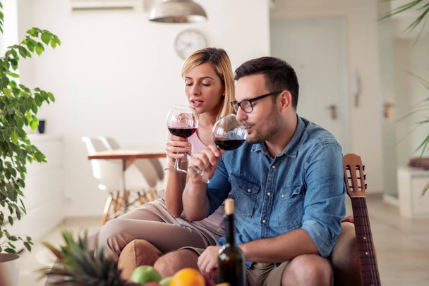 Пара пьющих красное вино в гостиной дома
. - Фото, изображение