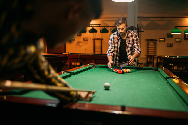 Due giocatori di biliardo maschili con stecca al tavolo con palline colorate. Gli uomini giocano a biliardo americano nello sport bar
 - Foto, immagini
