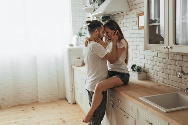 Beautiful loving couple kissing in kitchen - Фото, зображення