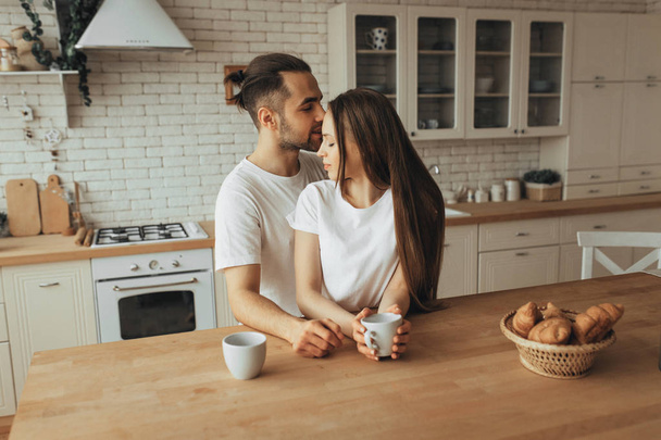 Beautiful loving couple kissing in kitchen - Foto, afbeelding