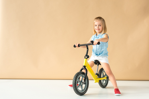 Enfant souriant en chemise et short à vélo sur fond beige
  - Photo, image