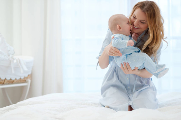 Happy middle aged mother with her child in a bed - Photo, Image