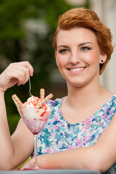 Attractive young woman eats ice cream outdoors - Photo, Image