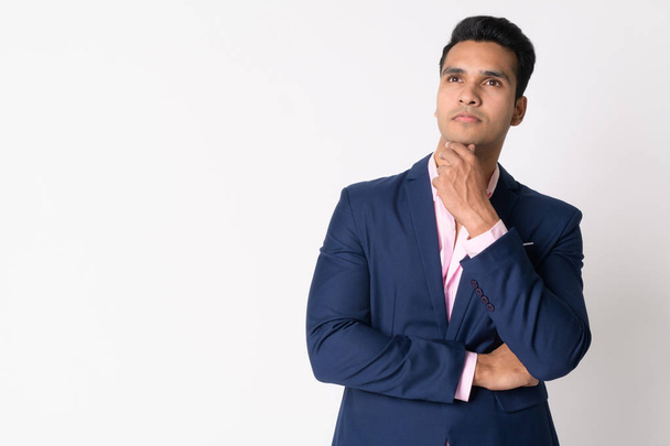 Portrait of young handsome Indian businessman in suit thinking - Foto, imagen