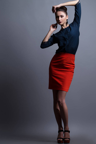 High fashion look. Portrait of a fashionable model with sexy red lips, beautiful red skirt and blue shirt. Studio shot - Zdjęcie, obraz