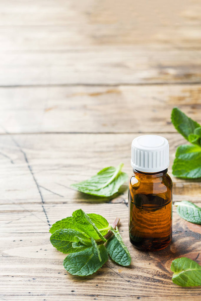 Essential aroma oil with peppermint on wooden background. Selective focus, copy space. - 写真・画像
