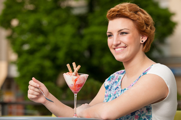 Attractive young woman eats ice cream outdoors - Photo, Image