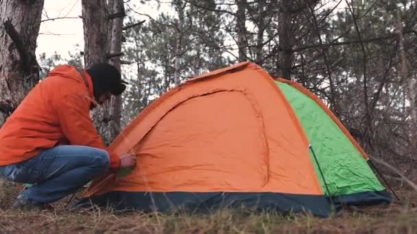 De reiziger een toeristische tent opgezet voor de nacht en voorbereid op bed. Rusten in het wild. - Video