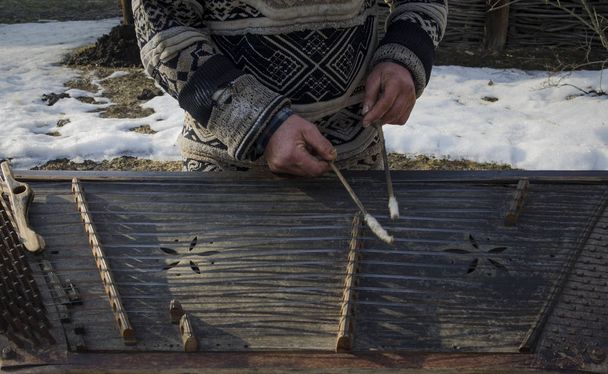Руки грязного старого уличного музыканта играют на старом музыкальном инструменте
 - Фото, изображение