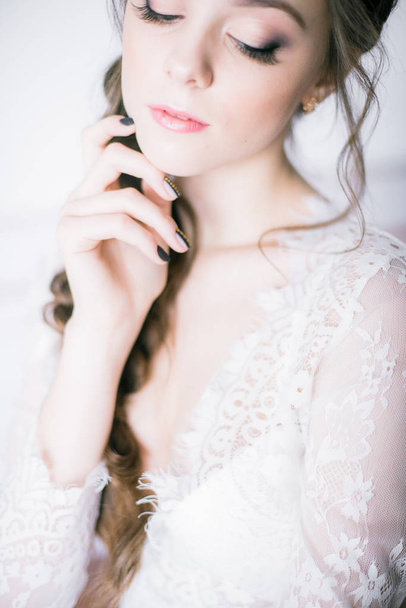Young cute bride with beautiful hair in the morning at home in white lace negligee - Φωτογραφία, εικόνα
