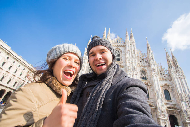 イタリアの旅行や休暇のコンセプト - ミラノ ドゥオモ大聖堂の前でセルフ ポートレートを撮影満足している観光客 - 写真・画像