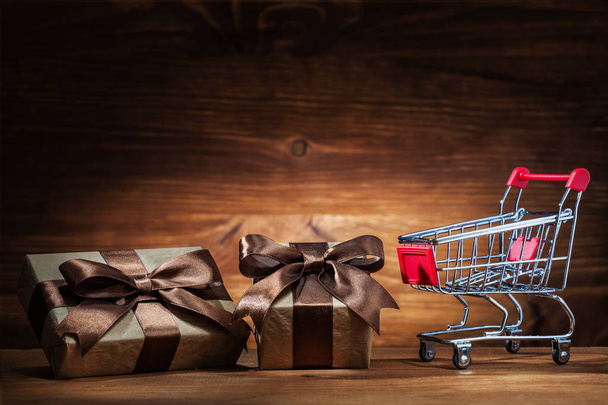 two giftboxes and shopping cart on vintage wood - Foto, afbeelding