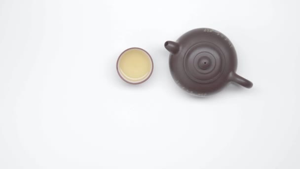 chinesische Tasse mit Tee und Wasserkocher auf weißem Hintergrund. Statischer Schuss. Teezeremonie. Teil 25. - Filmmaterial, Video