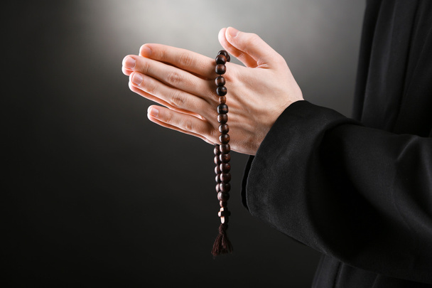 Priest holding rosary, on black background - Fotografie, Obrázek