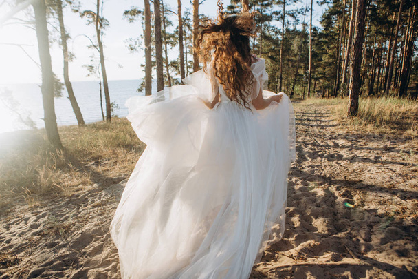 girl bride runs sand trees overlooking sea - Foto, imagen