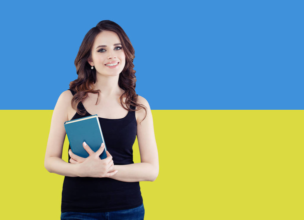 Happy brunette woman on the Ukrainian flag background.  - Foto, Imagem