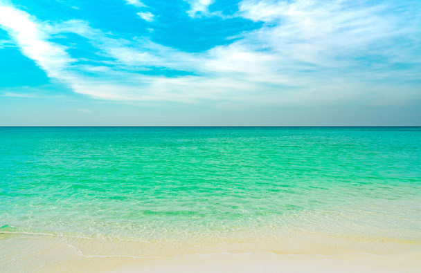 Playa de arena dorada junto al mar con agua de mar verde esmeralda y cielo azul y nubes blancas. Vacaciones de verano en concepto de playa paraíso tropical. Onda de agua salpicada en la playa de arena. Vibraciones de verano.  - Foto, Imagen